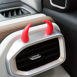 Petites cornes rouges fixées sur une grille d'aération intérieure de voiture