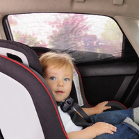Enfant installé dans un siège auto à l’arrière protégé du soleil par un pare-soleil de vitre arrière